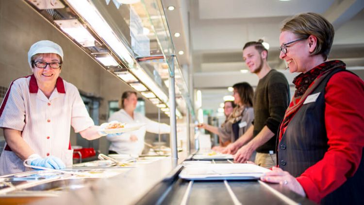 Servicepersonal gibt Essen an Patienten aus