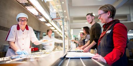 Servicepersonal gibt Essen an Patienten aus