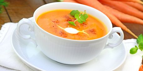 Karottensuppe mit Sahnehaube in einer antiken Suppentasse