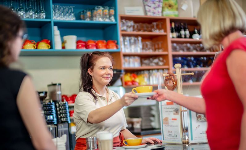 Servicekraft serviert eine Tasse Kaffee im klinikeigenen Café