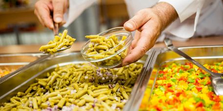 Koch füllt Gemüse am Buffet in eine kleine Schale